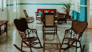 Amplia habitación con suelo de baldosas, una zona de estar central con sofá y sillones, y un candelabro.