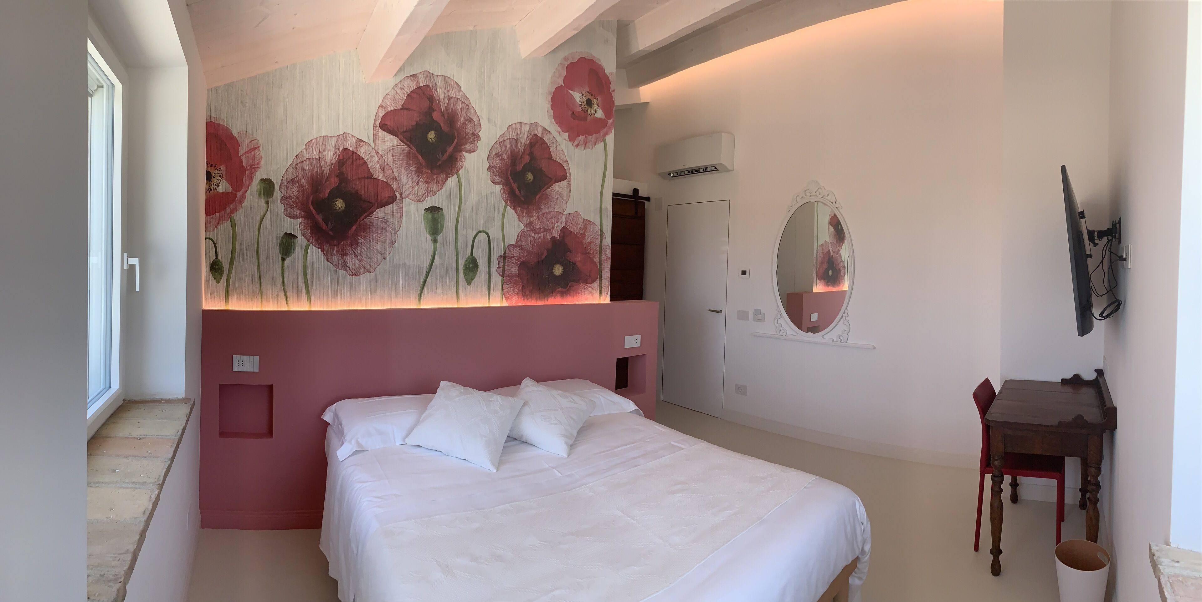 A bedroom with a large bed, a wall-mounted mirror, and a door.
