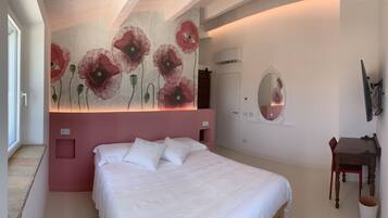 A bedroom with a large bed, a wall-mounted mirror, and a door.