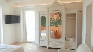 A bedroom with a bed, a wardrobe with a mirror, and a television on the wall.