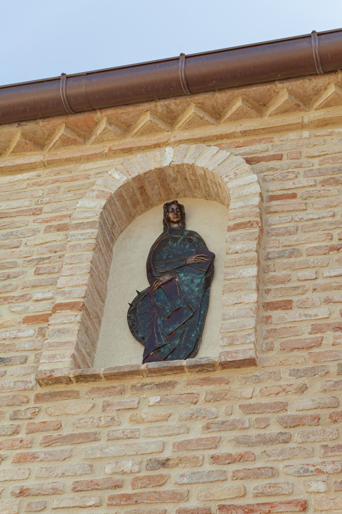 Estátua de uma figura em uma moldura embutida em uma parede de tijolos.