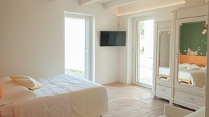 A bedroom with a bed, a TV mounted on the wall, and a wardrobe. - Frantoio L'Olinda (San Marcello)