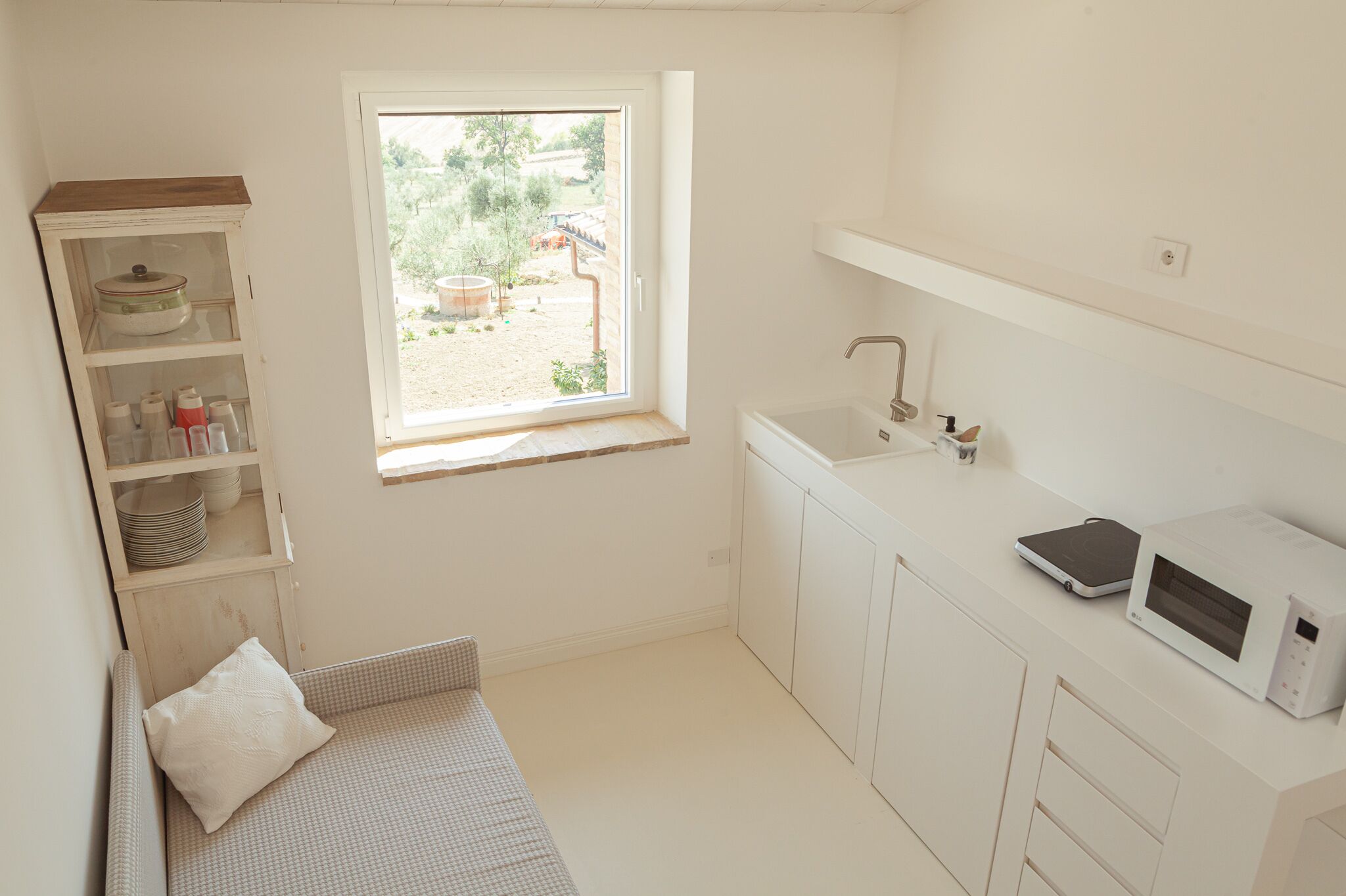 A small, bright kitchen with a window, a sink, and a microwave.