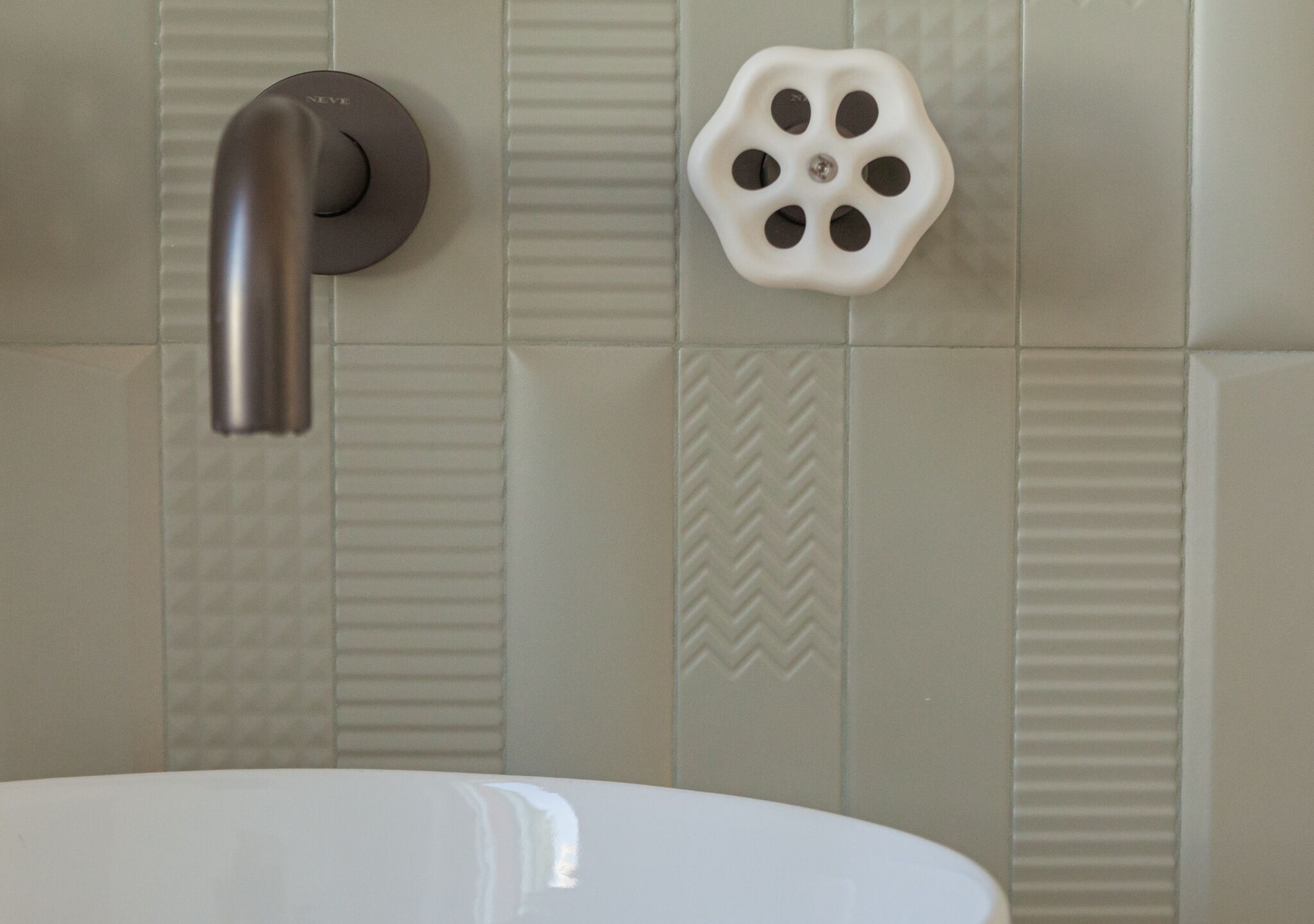 Un baño con un lavamanos blanco, un grifo moderno y un jabonera decorativa.