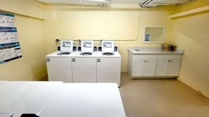 Un lavadero con cuatro lavadoras, un lavabo y armarios.