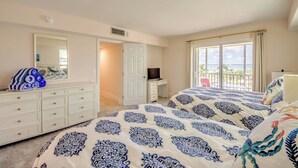 A bedroom with a bed, a dresser, a desk, a television, and a balcony with a view. - Vacation Villas #535 Cozy Beachfront Condo (Fort Myers Beach)