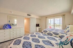 A bedroom with a bed, a dresser, a desk, a television, and a balcony with a view. - Vacation Villas #535 Cozy Beachfront Condo (Fort Myers Beach)