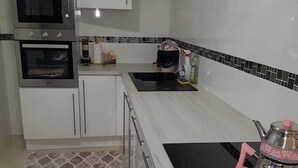 Een moderne keuken met witte kastjes, een magnetron, een oven, een spoelbak en een zwart inductiekookveld.