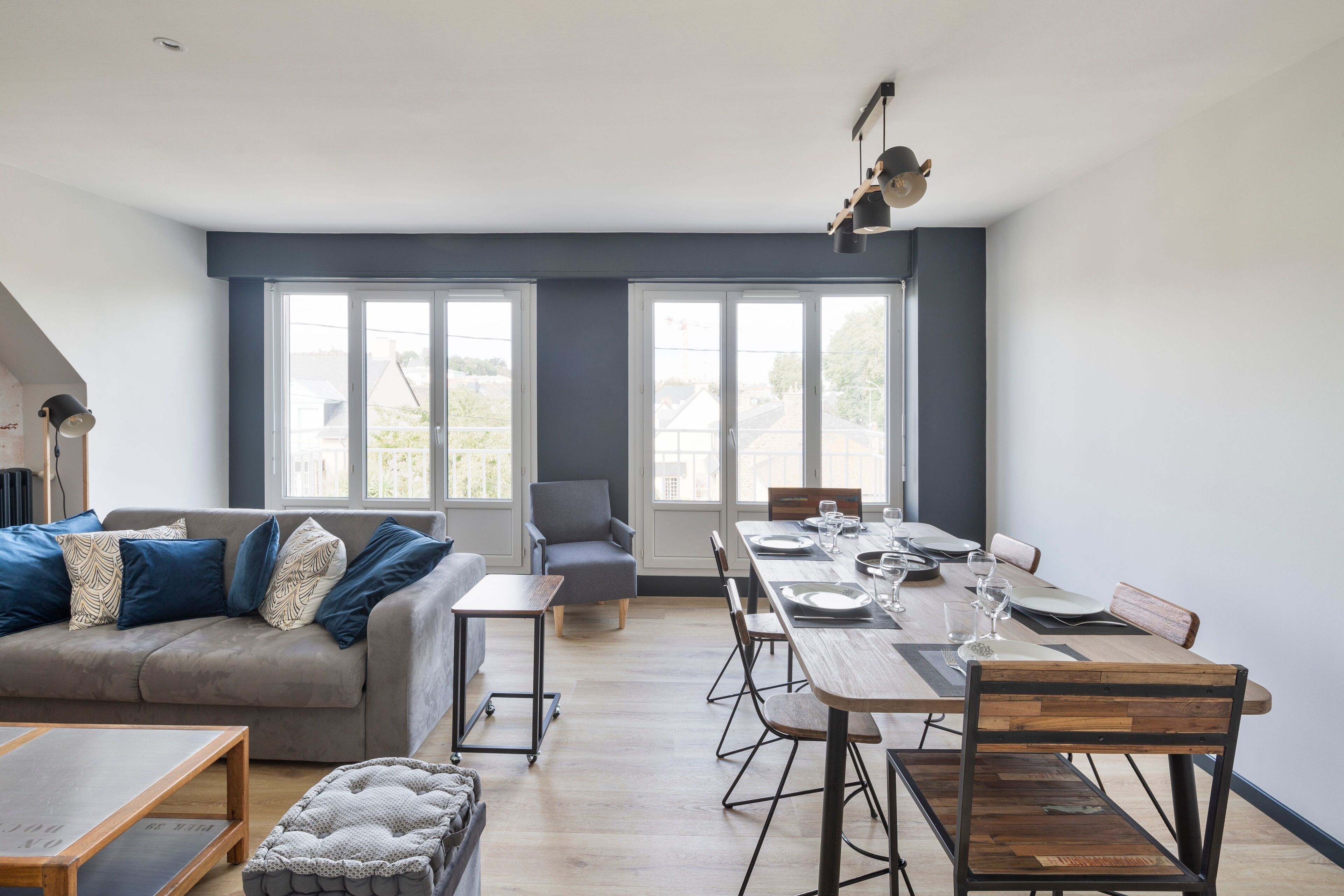 A modern living room with a sofa, a dining table set for four, and a small side table.