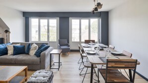Una sala de estar moderna con un sofá, una mesa de comedor para cuatro personas y una mesita auxiliar.