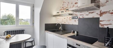 Et moderne køkken med et stort vindue, indbygget ovn og en sort bordplade.