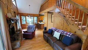 A cozy cabin interior with a fireplace, wooden floors, a brown leather sofa, and a staircase. - Bear Gone Fishing- Cool Down in the Creek!!! Mins to Highlands (Scaly Mountain)