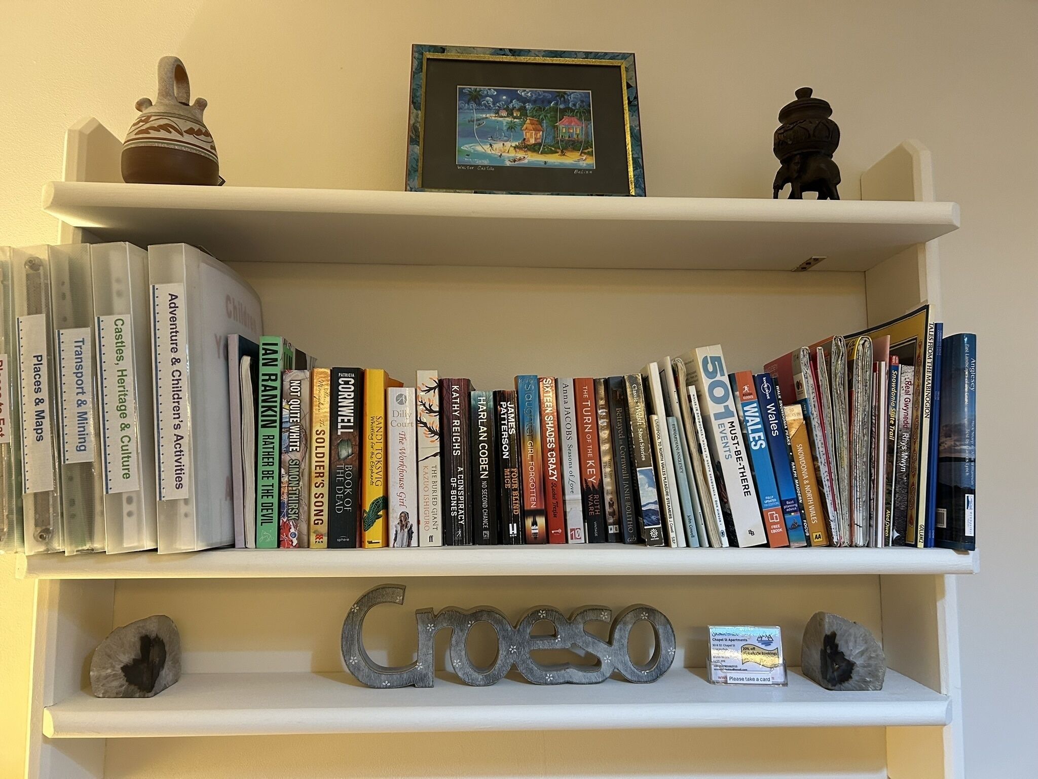 A bookshelf with various books, a framed picture, and decorative items.