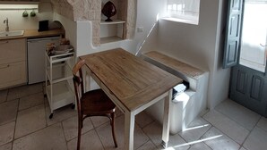 A rustic kitchen with exposed brick walls, a wooden table, and a window with curtains.