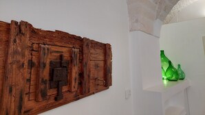 A rustic wooden wall panel with a metal latch, a stone archway, and a shelf with green glass bottles.