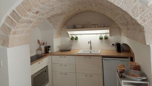 A kitchen with a stone arch, white cabinets, a sink, and a stove.