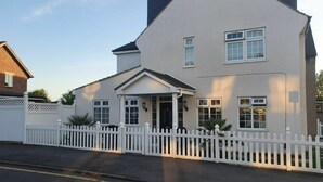 A two-story house with a white picket fence, a front porch, and a garage. - Amazing Ilford 3 bedroom house (Ilford)