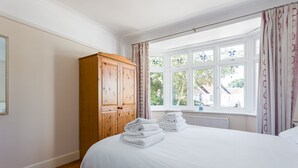 Een slaapkamer met een groot bed, een houten garderobe en een raam met gordijnen.