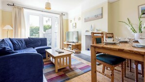 Een woonkamer met een bank, een salontafel, een televisie en een eethoek met een tafel en stoelen.