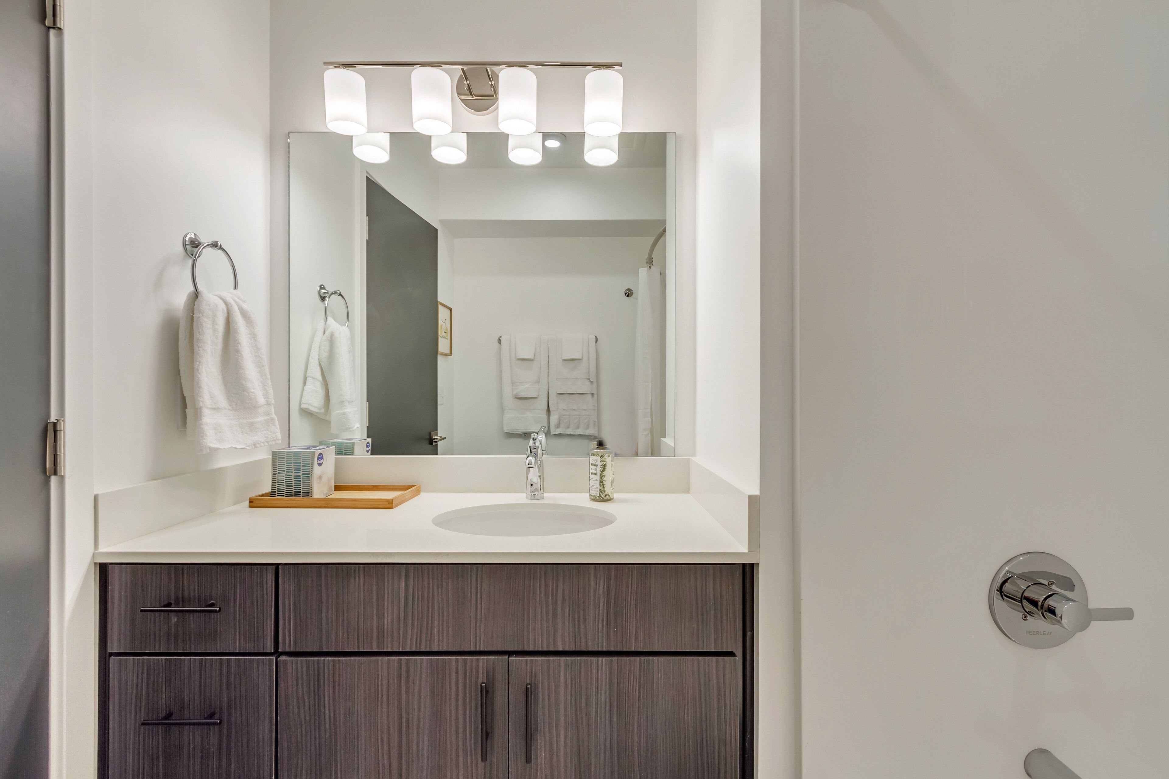 A modern bathroom with a large mirror, a sink, and a vanity with drawers.