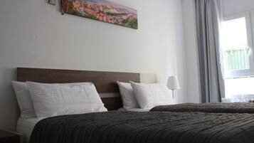 Une chambre d’hôtel avec deux lits, un tableau au mur, une lampe et une fenêtre avec des rideaux.