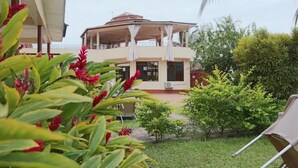 Un bâtiment à deux étages doté d’un espace extérieur couvert et d’un petit jardin.