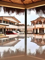 Un espacio interior amplio con piso reflectante, una zona de estar techada y un edificio con varios balcones y un coche rojo estacionado afuera.