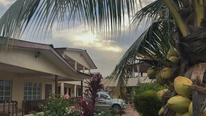 Un quartier résidentiel avec un chemin pavé, une voiture garée et une maison dotée d’un balcon.
