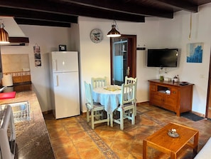 A compact living space with a dining area, kitchen, and a television.