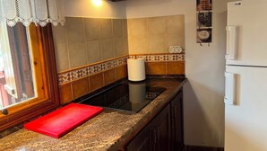 A kitchen with a red cutting board, a white refrigerator, and a patterned backsplash.