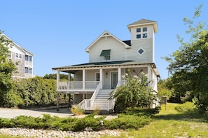 A two-story house with a porch and a small tower-like structure on the roof.