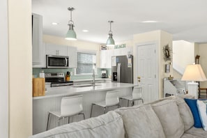 A modern kitchen with white cabinets, a central island, and bar stools.