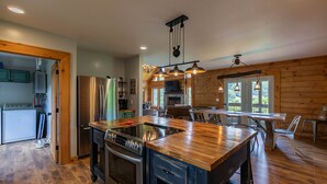 A modern kitchen with a central island, stainless steel appliances, and a dining area with a wooden table and chairs.