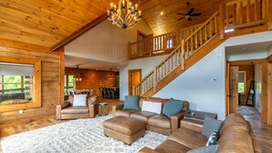 A spacious living room with a large sectional sofa, a fireplace, and a wooden staircase.