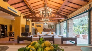 A cozy room with a wooden ceiling, a chandelier, a bed, a table with a fruit centerpiece, and a view of greenery outside. - Villa Cavalli - Private villa, 4 bedrooms, pool, A/C, wifi, nature, Marche (Vallefoglia)