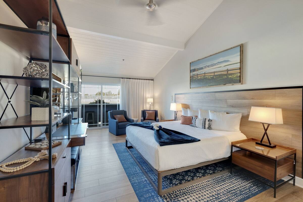 Una habitación de hotel moderna con una cama grande, un escritorio, una silla y un balcón con vistas.