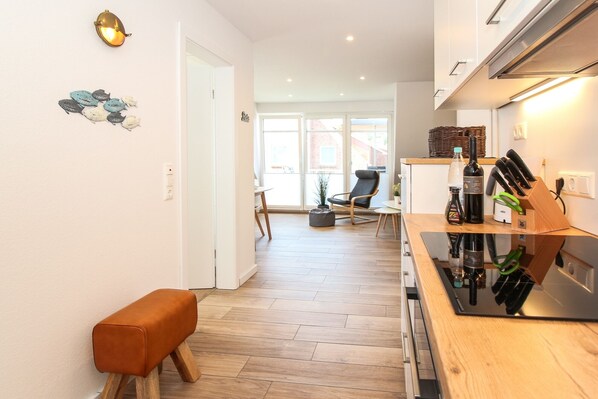 A modern kitchen with a wooden countertop, a bench, and a dining area with a chair.