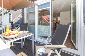 A balcony with a table set for a meal, a chair, and a bottle of water.