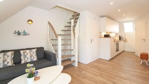 Een modern appartement met een trap, een zithoek met een bank en salontafel, en een keuken.