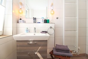 Une salle de bain moderne avec un lavabo blanc, un miroir et un porte-serviettes.