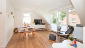 Een moderne, goed verlichte kamer met een eettafel, stoelen, een televisie en een groot raam met uitzicht.