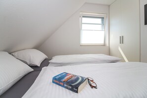 Une chambre avec deux lits, une fenêtre et un livre sur l’un des lits.