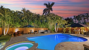 A swimming pool with a wooden deck, lounge chairs, and a wooden fence.