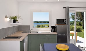 Eine moderne Küche mit Seeblick, einer integrierten Mikrowelle und einer Kaffeemaschine.