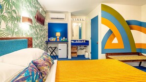 Une chambre d’hôtel avec un lit, un bureau, une chaise, un lavabo et un miroir.
