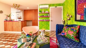 Un salon moderne avec un canapé bleu, une table basse agrémentée de livres et d’objets décoratifs, et un mur d’accent d’un vert éclatant.