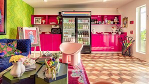 Un salon chaleureux et accueillant, avec un canapé bleu, un fauteuil rose et un tapis aux couleurs vives.