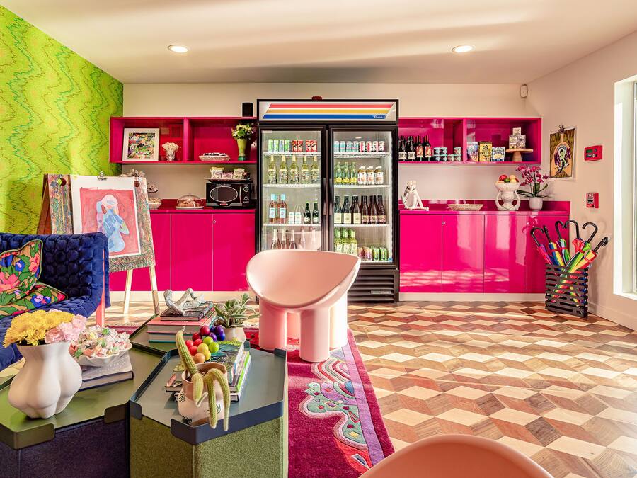 A vibrant living room with a blue sofa, a pink chair, and a colorful rug.