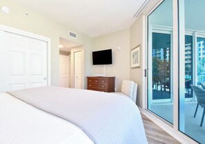 A bedroom with a bed, a dresser, a TV, and a sliding glass door leading to an outdoor balcony. - Resort Condo w/ Lagoon-Style Pool Views in Central Destin! ☀🌴🏖 (Destin)