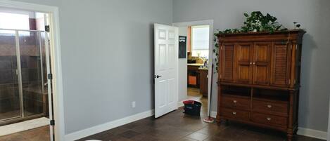Une chambre avec un grand lit, une armoire en bois et une porte-fenêtre coulissante donnant sur un espace douche.
